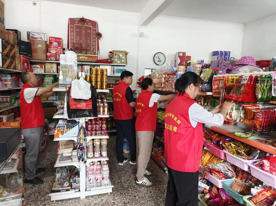 图为宜州烟草组织党员志愿者帮助困难零售户整理货物，亮化终端形象。覃业军 摄