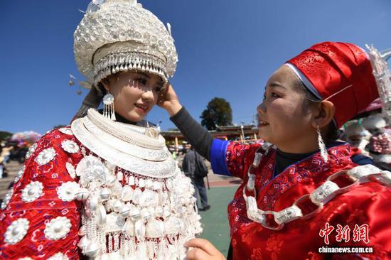 图为黄平谷陇“芦笙会”现场一名苗族妇女在给女儿整理着装。陈孝新 摄
