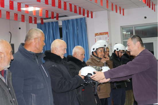 为柯坪县玉尔其乡杏花村第一书记为村民发放安全头盔。