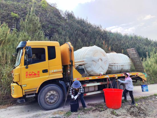 图为烟农正在给烟田送水“保命水”。杨绍基 摄