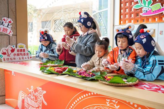 图为“小候鸟”戴上童帽制作五色糯米饭拼图。谈婕 摄