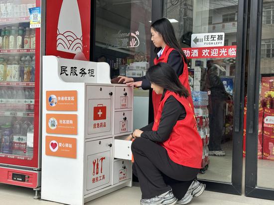 上林烟草营销人员帮助“丹八桂”零售客户整理便民服务箱。燕东雨 摄