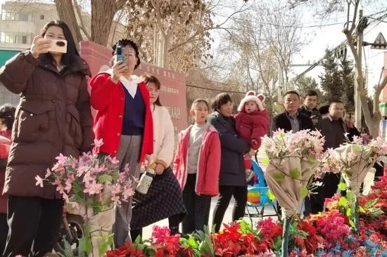 沿途群众用手机记录社火巡演精彩瞬间。