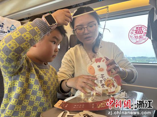 图为：旅客在列车上制作喜庆挂件。中新社发 高艳 供图