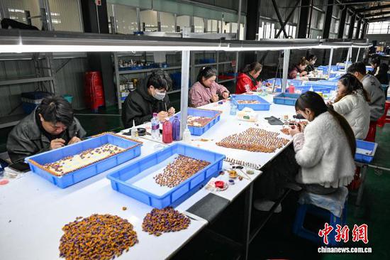 3月10日，工人在贵州省黔南州独山经济开发区的一家玩具生产企业车间加工产品。连日来，独山经济开发区内的多家玩具生产企业满负荷运转，赶制海外订单，以保障市场供应。中新社记者 瞿宏伦 摄