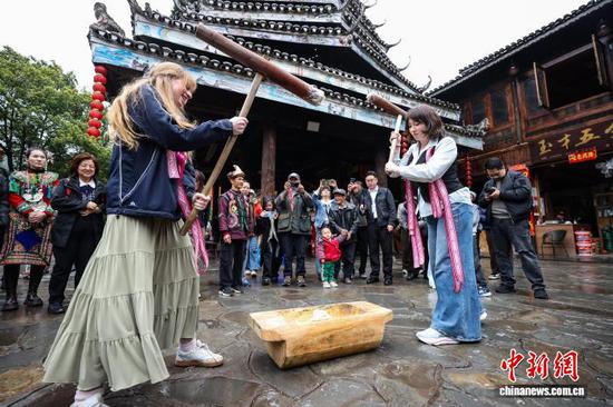3月23日，耶鲁大学Whiffenpoofs合唱团成员在肇兴侗寨体验打糍粑。中新社记者瞿宏伦摄