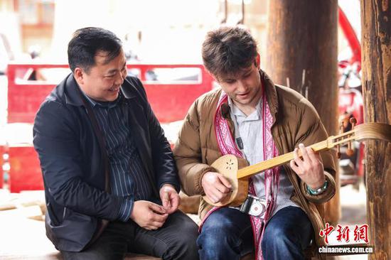 3月23日，耶鲁大学Whiffenpoofs合唱团成员在肇兴侗寨学习侗族琵琶。中新社记者瞿宏伦摄