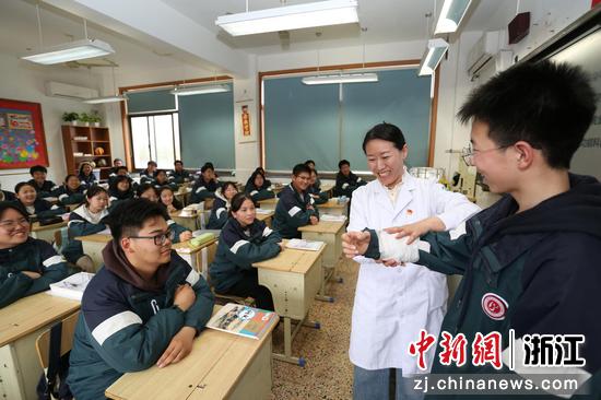 图为：护士长为学生讲解和模拟包扎方法。中新社发 单明铭 摄