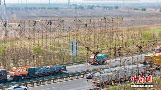 图为国网天津市电力公司工作人员在大同~天津南1000千伏特高压交流线路工程（天津段）现场进行跨越长深高速封网作业。　李亚君 　摄