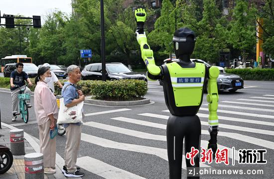 
图为：维护交通秩序的“985”号AI交管机器人吸引行人关注。中新社记者 王刚 摄