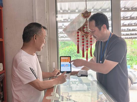 图为工作人员在手把手教黄达松使用云POS。 黄敏华 摄