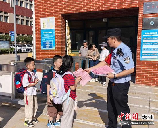 图为北京铁路公安局天津公安处民警正在给学生发放爱路护路宣传单。（北京铁路公安局天津公安处供图）